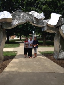 Judy Freundt Zawacke, Paula Bloomquist Wayland, and Jill Wyatt Dew enjoy a moment under one of the sculptures on loan to IWU this fall.