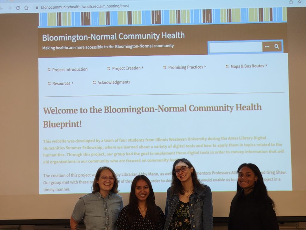 Leah Matlin, Alex Dawson, Amanda Balaba, and Amber Anderson stand in front of a screen with the project's website projected behind them.