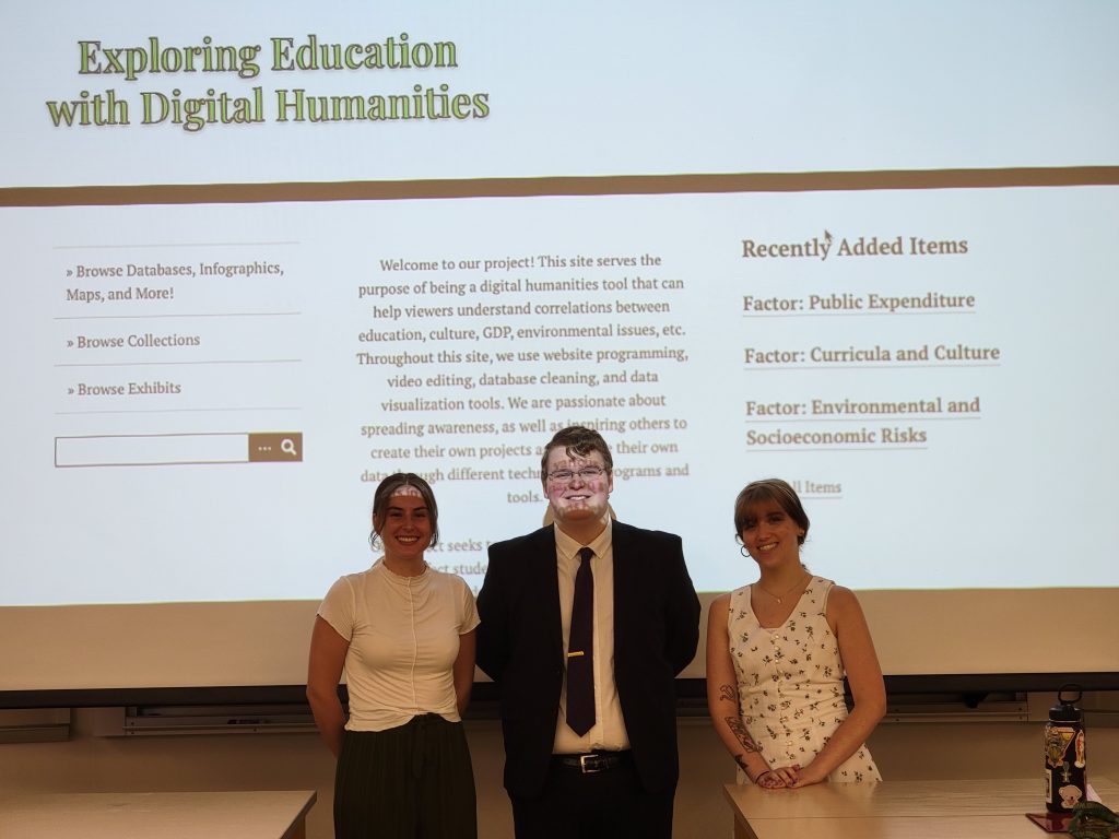 Kacie Moore, Zoe Hodve, and Josh Reed stand in front of a screen with their project's website showing behind them.
